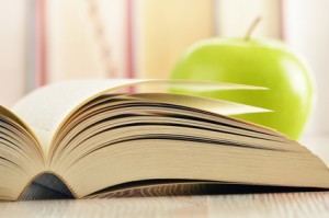 Composition with green apple and books on the table